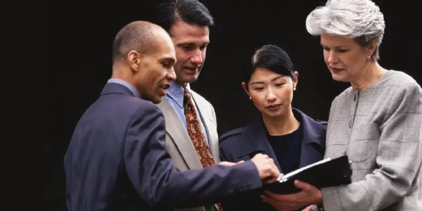 Group of men and women looking at an open book together
